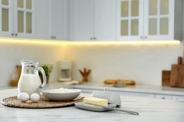 Sticker - Different dairy products and eggs on white table in modern kitchen. Space for text