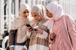 © Santi Nunez/Stocksy - Three muslim women looking at a mobile phone.