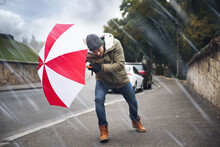 Man With Colorful Umbrella Caught In Gust Of Wind On Street