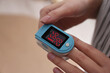 © New Africa - Woman measuring oxygen level with modern fingertip pulse oximeter indoors, closeup