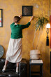 © Alina Hvostikova/Stocksy - Woman hanging artwork on wall