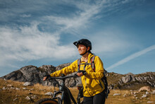 Smiling Woman Walking With Electric Mountain Bike Against Mountain At Somiedo Natural Park, Spain
