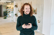 © Jo Kirchherr/Westend61 - Cheerful mid adult man looking away while using mobile phone at studio apartment