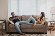 © Sara Monika/Westend61 - Couple using mobile phone while sitting on sofa at home