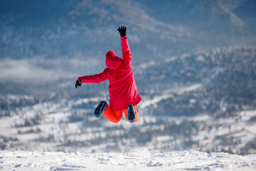 Alpine skier jumping against the background of a winter mountain landscape.