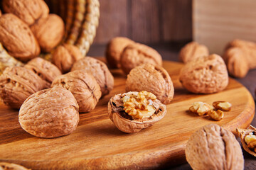 Poster - Walnuts in a wicker basket, whole and finely chopped, next to the filling and shells on a wooden background. Home storage of winter preparations