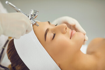 smiling womans face getting oxygen therapy or jet peeling from cosmetologist