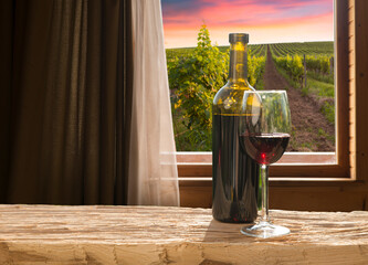 Glass of red wine standing on windowsill with autumn leaves and a fogged window in the background