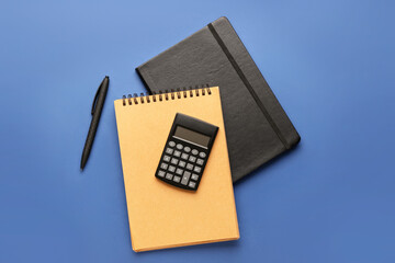 Digital calculator, notebooks and pen on color background