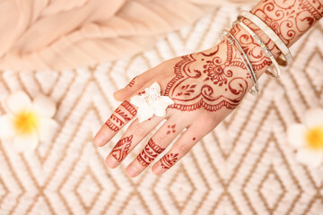 Wall Mural - Beautiful female hand with henna tattoo and flower on light background