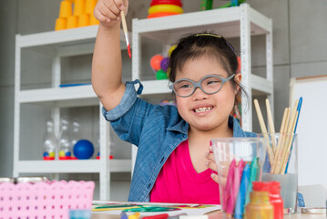 Portrait of young Asian disabled child complex genetic disorders girl draw a picture with watercolor in element classroom