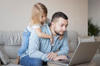 © Julija - Man working from home with laptop during quarantine. Home office and parenthood at same time. Exhausted parent with hyperactive child.