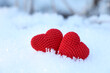Valentine's hearts on a snow in winter forest. Two red knitted symbols of love, background for romantic greeting card