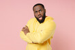 © ViDi Studio - Side view of shocked worried young african american man 20s wearing casual basic yellow streetwear hoodie holding hands crossed looking camera isolated on pastel pink color background studio portrait.