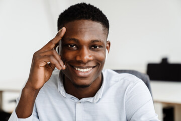 Poster - Afro american joyful man in earphones smiling at camera