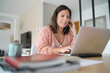 © goodluz - young brunette latin woman working on laptop at home