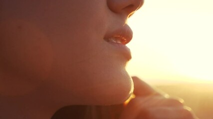 Wall Mural - dream face of a beautiful girl lips hair fluttering in the wind in the sunlight dream of happiness. people in the park concept. model face lips strong close-up wind hair swaying in the park