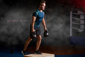 Poster - Attractive sportsman with kettle bell exercise in the fitness gym on the color smoke background. Copyspace area for advertise slogan or text message. Functional training and crossfit concept.