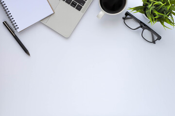 Workplace in office with white desk. Top view above of keyboard computer with coffee cup and glasses. Space for modern creative work of designer. Flat lay with copy space. Business-finance concept.