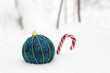 Christmas toy ball with candy cane on the snow in winter forest. Background for New Year celebration, greeting card