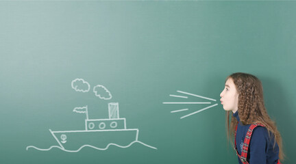 Pre-adolescent girl blowing on painted sailing ship