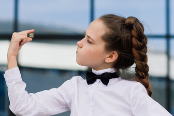 Portrait of cute caucasian teen girl holding coin. Saving money concept.