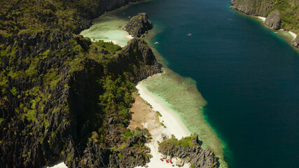 Tropical landscape bay with beach and clear blue water surrounded by cliffs, aerial drone. El nido, Philippines, Palawan. Seascape with tropical rocky islands, ocean blue water. Summer and travel