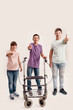 Full length shot of three disabled children with Down syndrome and cerebral palsy smiling, showing thumbs up while standing together isolated over white background