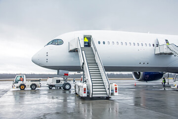 Wall Mural - Wide body aircraft with ladder stairs to the airport parking.