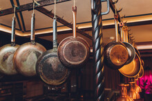 Old Kitchen Pans Hanging On The Bar. Different Size Of Pans On The Wall, Home Decoration, Kitchen Background.