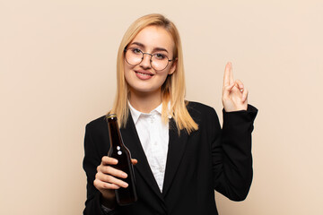 Wall Mural - young blonde woman looking happy, confident and trustworthy, smiling and showing victory sign, with a positive attitude