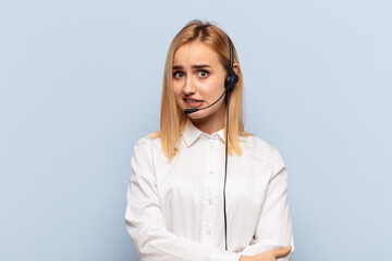 Wall Mural - young blonde woman doubting or thinking, biting lip and feeling insecure and nervous, looking to copy space on the side