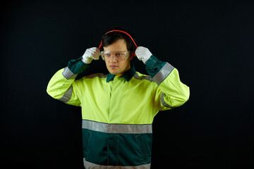 Builder puts on personal protective equipment. A worker wearing safety glasses and gloves puts on earplugs. The use of PPE at the factory