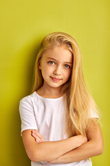 portrait of attractive open-minded teen girl with long hair isolated over green studio background, beautiful child smiling at camera, with crossed hands, folded hands