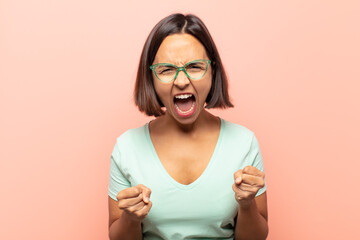 Sticker - young hispanic woman shouting aggressively with annoyed, frustrated, angry look and tight fists, feeling furious