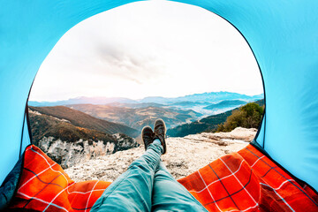 Wall Mural - Man lying in a tent with the view of mountains and sunset - Sport, travel and lifestyle concept.