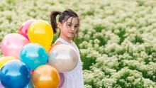 Girls Playing With Balloons On The Grass And In A Field Of Flowers On A Sunny Day Enjoying And Smiling
