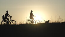 Friendly Family With A Child On Bicycles During Sunset.