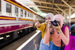 Female Islamic tourists take fun photos on the train platform while waiting for their journey.