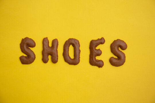 Word SHOES arranged from homemade chocolate cookie  alphabet on yellow table