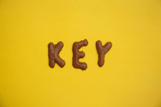 Word KEY arranged from homemade chocolate cookie  alphabet on yellow table