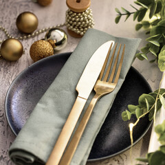 Wall Mural - Table setting with ceramic plate, gold cutlery , and eucalypt brunch for Merry Christmas and Happy New Year celebration .Beautiful  festive dinner tableware.Close up