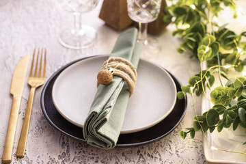 Festive table setting with ceramic plate, gold cutlery , garland and eucalypt brunch. Merry Christmas and Happy New Year celebration concept.