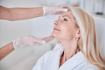 Attractive smiling lady sitting on beauty couch and looking to the doctor in beauty clinic