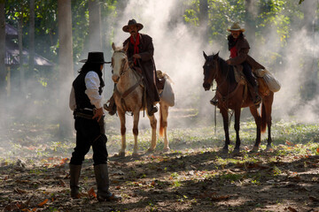 Vintage portrait of three cowboy men riding a gunfighting horse. In a forest