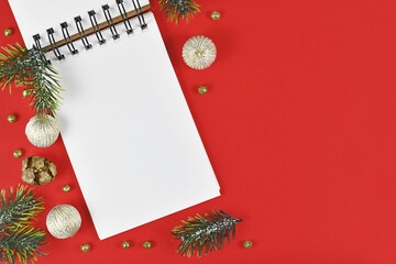 Wall Mural - White empty notebook surrounded by Christmas decoration in corner of red background with empty copy space