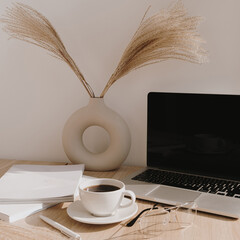 Wall Mural - Female home office desk workspace. Blank screen laptop computer with copy space. Coffee cup, pampas grass in stylish vase on beige wooden table. Minimalist lifestyle blog mockup.