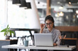 © Prathankarnpap - An attractive elegant businesswoman working with computer laptop and  touching the black rim of glasses.