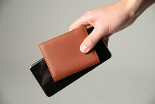 Hand Holding A Leather Wallet And A Cell Phone