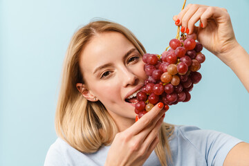 Poster - Pleased charming blonde girl eating grape on camera